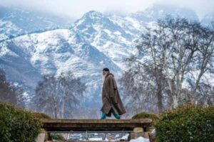 Kashmiri Man in Snow traditional attire with Himalayan backdrop
